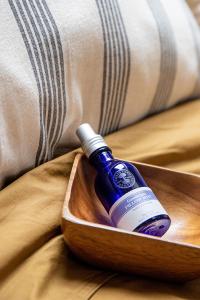 a bottle of blue liquid in a wooden bowl on a bed at Studio Spiegelhof in Ghent
