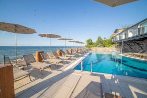 a pool with chairs and umbrellas next to the ocean at Atik Hotel in Unye