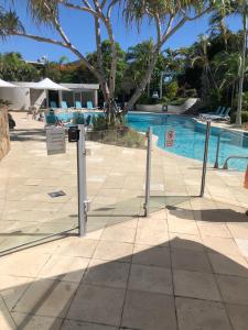 una piscina con tres postes de metal delante en Carramah Noosa Heads apartment en Noosa Heads