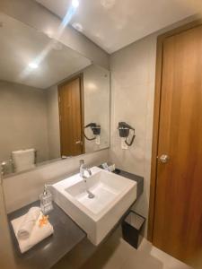 baño con lavabo y espejo grande en BeSS Mansion Hotel Surabaya en Wonocolo