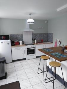 een keuken met witte apparatuur en een tafel en stoelen bij Gîte des trois vallees in Nouzonville