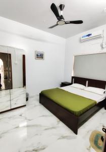 a bedroom with a green bed and a ceiling fan at Vedganga Villa - Homestay in Kolhapur