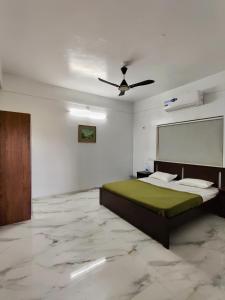 a bedroom with a bed and a ceiling fan at Vedganga Villa - Homestay in Kolhapur +3 photos