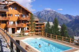 a hotel with a swimming pool with mountains in the background at T2 Cosy à 50m des pistes, 6 pers Puystvincent 1800 in Puy-Saint-Vincent