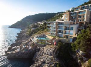 a building on a cliff next to the water at Apartment Your Home in Dobra Voda