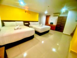 a hotel room with two beds and a yellow wall at N HIBISCUS HOTEL in Seri Kembangan