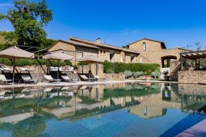 a pool with chairs and umbrellas in front of a house at Borgo Canalicchio Di Sopra Relais in Montalcino