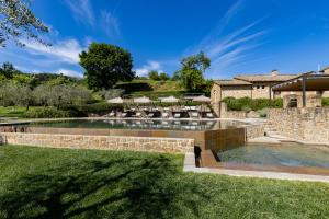 uma piscina com cadeiras e guarda-sóis num quintal em Borgo Canalicchio Di Sopra Relais em Montalcino