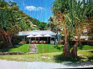 a house with palm trees in front of it at Carramah Noosa Heads apartment in Noosa Heads