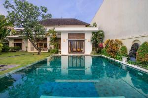 a swimming pool in front of a house at Bali Villa Lotus in Seminyak