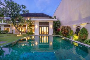 a villa with a swimming pool in front of a house at Bali Villa Lotus in Seminyak
