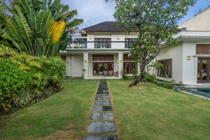 a house with a green yard with a pathway at Bali Villa Lotus in Seminyak