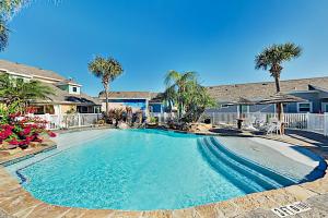 uma grande piscina com palmeiras num quintal em Mermaid Cove at Pirate's Bay unit 209 em Port Aransas