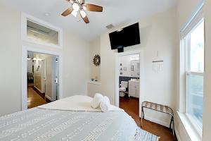a white bedroom with a bed and a flat screen tv at Mermaid Cove at Pirate's Bay unit 209 in Port Aransas