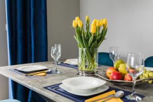 a table with yellow tulips in a vase on it at Tarasowy Apartamenty Luksusowe in Olsztyn