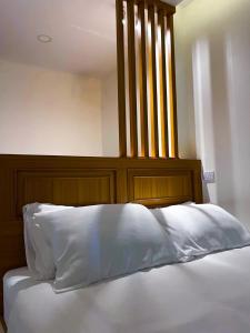 a bed with a wooden headboard and a white pillow at TJ Boutique Hotel in Uthai Thani