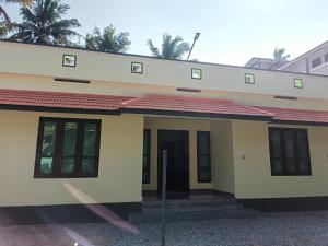 a small yellow house with a red roof at isha homestay in Varkala