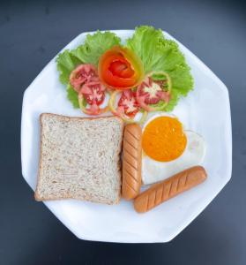 a white plate with an egg and a sandwich and carrots at TJ Boutique Hotel in Uthai Thani