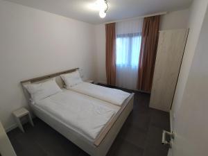 a bedroom with a bed with white sheets and a window at Domacinstvo Kod Gere in Crni Vrh