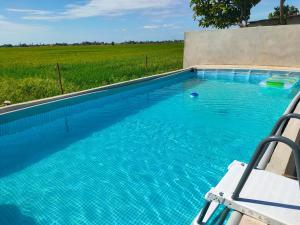 una piscina con una silla y un campo en Homestay Anjung Malinja Private Pool Kedah, en Yan