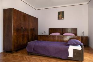 Un dormitorio con una gran cama de madera con sábanas moradas. en Vintage Apartment Nona en Mošćenička Draga