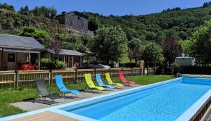 a row of chairs sitting next to a swimming pool at Camping Le Jardin - chalets, bungalows et emplacements nus pour des vacances nature le long de la rivière le Gijou in Lacaze