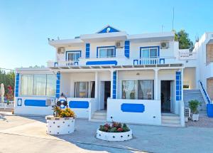 een blauw en wit huis met bloemen ervoor bij Apollonio Suites & Rooms Faliraki Rhodes in Faliraki