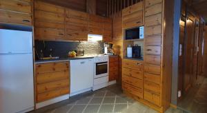 una cucina con elettrodomestici bianchi e armadietti in legno di Vuosselin Tähti a Ruka