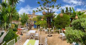 a patio with tables and chairs in a garden at Alacati Kayezta Hotel in Alaçatı