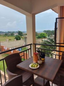 a table with a plate of fruit on a balcony at Glen's Apartment in Entebbe