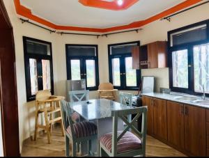 a kitchen with a table and chairs and windows at Glen's Apartment in Entebbe