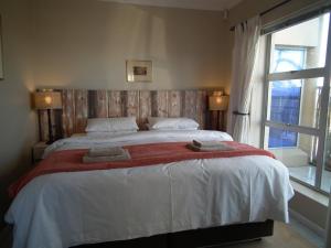 a bedroom with a large bed with two towels on it at 78on5th in Hermanus in Hermanus