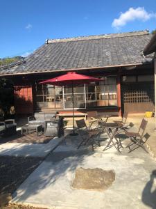 a patio with a table and chairs and an umbrella at Kumano Winery Guest House in Tanabe