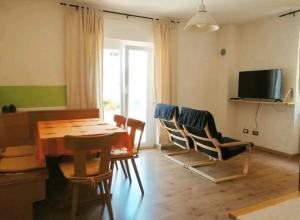 sala de estar con mesa, sillas y TV en Appartamenti Viola, en Cavedago
