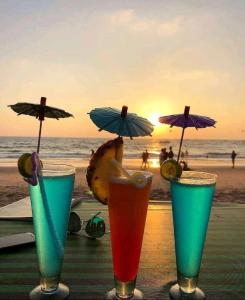 grupa trzech drinków siedzących na stole na plaży w obiekcie Shiva Cottages w mieście Mandrem