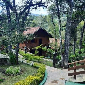 una casa con una pasarela frente a un jardín en Hotel Pião Mineiro, en Monte Verde