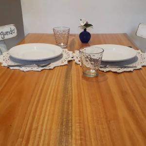 a wooden table with two plates and glasses on it at Arboleda Monoambiente in El Hoyo