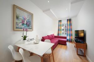 ein Wohnzimmer mit einem weißen Tisch und einer rosa Couch in der Unterkunft Deluxe Apartment 35qm im Design Hotel Vosteen in Nürnberg
