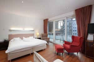 a hotel room with a bed and a red chair at 35qm Deluxe Apartment Suites im Stil Design Hotel Vosteen Nähe der Kaiserburg in Nürnberg