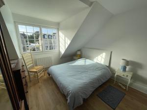 une chambre blanche avec un lit et une fenêtre dans l'établissement L'Appartement de la Plage, à Saint-Quay-Portrieux