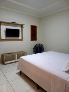 Pousada Império في ساو ميجيل دو غوستوسو: غرفة نوم مع سرير وتلفزيون على الحائط