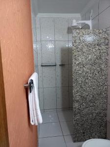 La salle de bains est pourvue d'une douche avec une porte en verre. dans l'établissement Pousada Império, à São Miguel do Gostoso