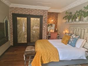 a bedroom with a bed and a brick wall at La Casa Nostra Villa Rose Garden Carmella in Hillcrest