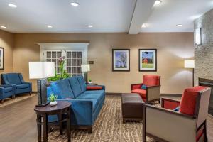 sala de estar con sofá azul y sillas en Comfort Inn & Suites Northern Kentucky en Wilder