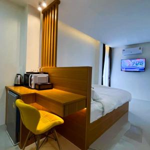 a small bedroom with a bed and a yellow chair at TJ Boutique Hotel in Uthai Thani