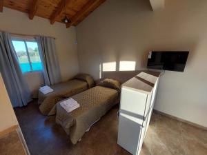 sala de estar con 2 camas y TV de pantalla plana en Cabañas Mágico Atardecer en San Rafael