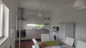 een keuken met een tafel en een keuken met witte apparatuur bij Casa da Bia - AL em Arcos de Valdevez in Arcos de Valdevez