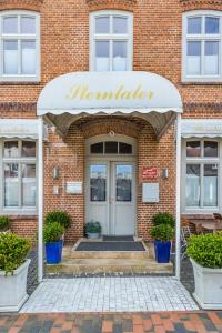 une porte d'entrée d'un bâtiment en briques avec un panneau indiquant une fresque murale dans l'établissement Aschenputtel, à Westerland