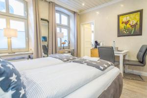 1 dormitorio con 2 camas, escritorio y ventanas en Aschenputtel, en Westerland
