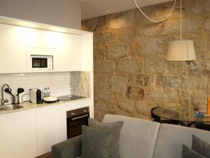 cocina con mesa y pared de piedra en MSC Flats - Comercio do Porto, en Oporto